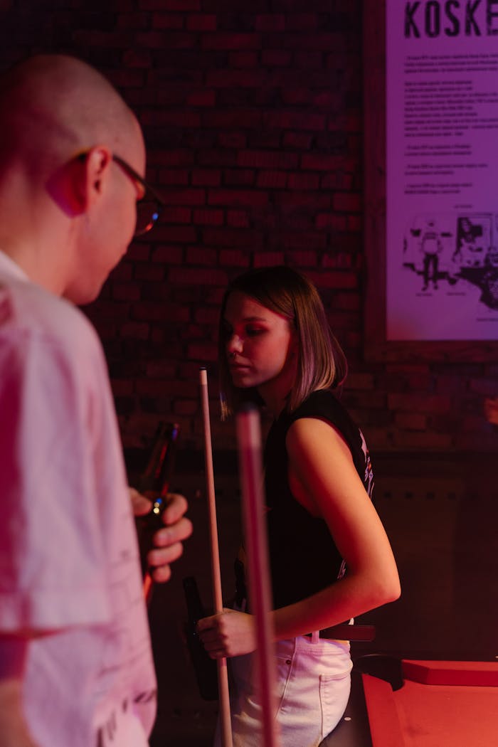 services-03 Charming night scene of a young couple playing billiards in a lively bar setting.